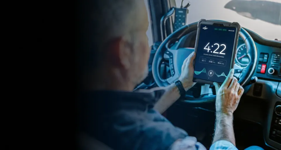 A driver holding a FleetTab showing hours of drive time remaining